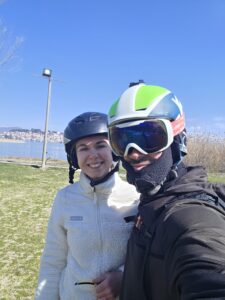 Pilot and passenger posing for a selfie by the shore of Lake Ohrid after a successful tandem paragliding landing.